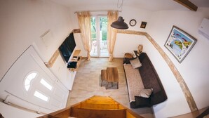 Ein großzügiger Wohnbereich mit einer Holztreppe, einem Sofa, einem Couchtisch und einem Esstisch.
