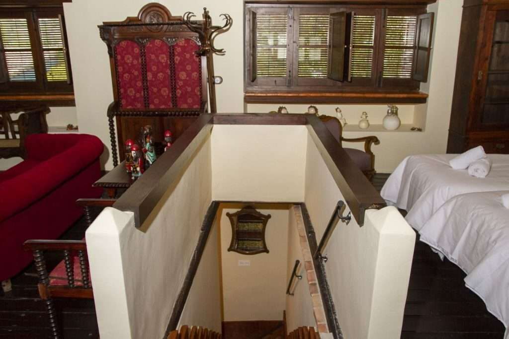 Una escalera estrecha que lleva a un dormitorio con una cama y un sillón rojo.