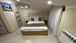 A bedroom with a bed, bedside tables, a radiator, and a picture on the wall. - BARHAT HOTEL (Tashkent)
