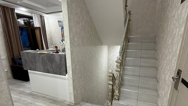A modern interior with a staircase, a kitchen area, and a dining space. - BARHAT HOTEL (Tashkent)