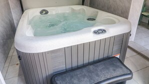 Un bain à remous doté d’un panneau de commande, un panneau de commande pour la douche et une étiquette d’avertissement fixée au mur.