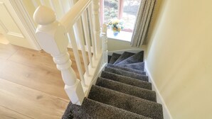 Un escalier avec des balustrades blanches et des marches recouvertes de moquette, menant à un palier.
