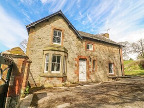 A stone house with a gabled roof, a central door, and a small porch. - South Lodge (Appleby-in-Westmorland)