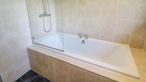 A modern bathroom with a freestanding bathtub, a handheld showerhead, and a glass-enclosed shower area. - South Lodge (Appleby-in-Westmorland)