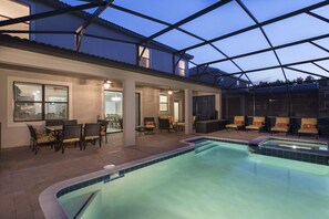 A swimming pool with a glass ceiling, outdoor seating, and a patio area.