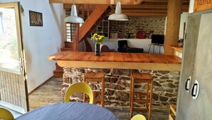 A rustic kitchen with a wooden island, stone walls, and a staircase leading to an upper level. - Renovated stone house, Plouzelambre, Côtes d'Armor (PLOUZELAMBRE)
