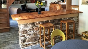 A rustic kitchen with a wooden island, stone walls, and a staircase leading to an upper level. - Renovated stone house, Plouzelambre, Côtes d'Armor (PLOUZELAMBRE)