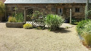 A stone building with a sloped roof, two small windows, and a wooden gate. - Renovated stone house, Plouzelambre, Côtes d'Armor (PLOUZELAMBRE)