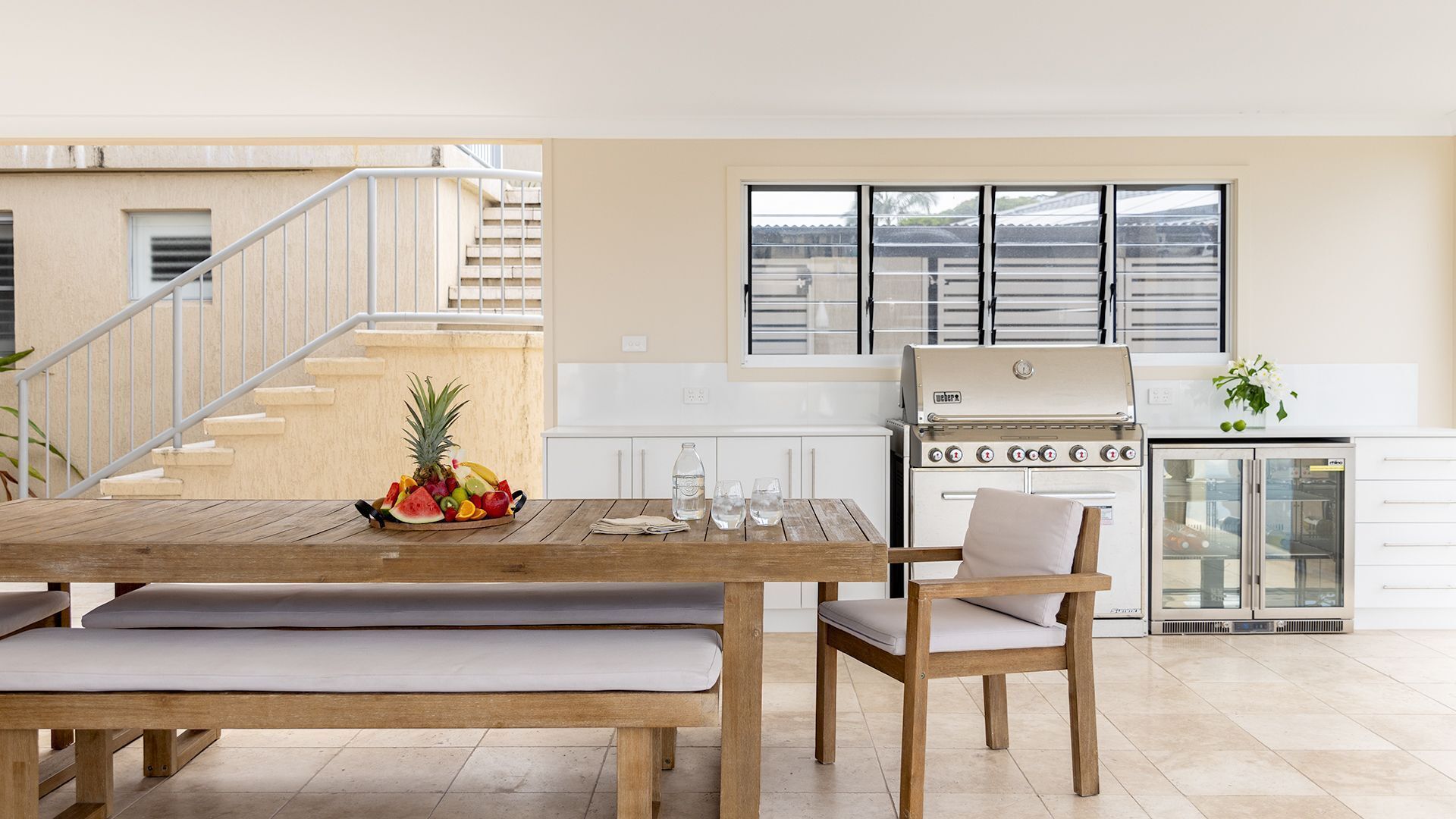 A modern kitchen with a wooden table, a bench, and a fruit bowl.