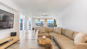 Un salon moderne avec un grand canapé d’angle, un téléviseur à écran plat et une table basse en bois.