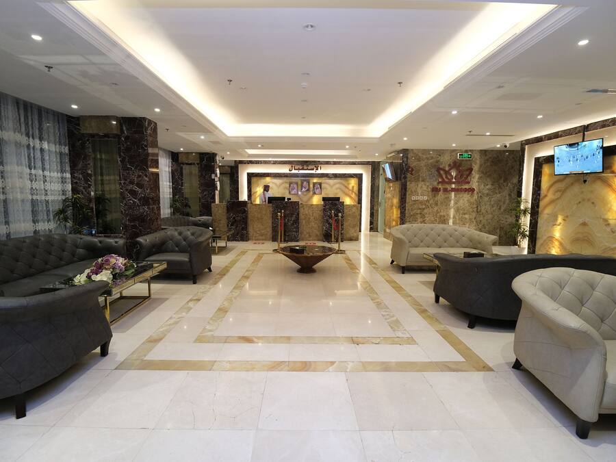 A spacious lobby with a reception desk, plush seating, and a large TV screen.