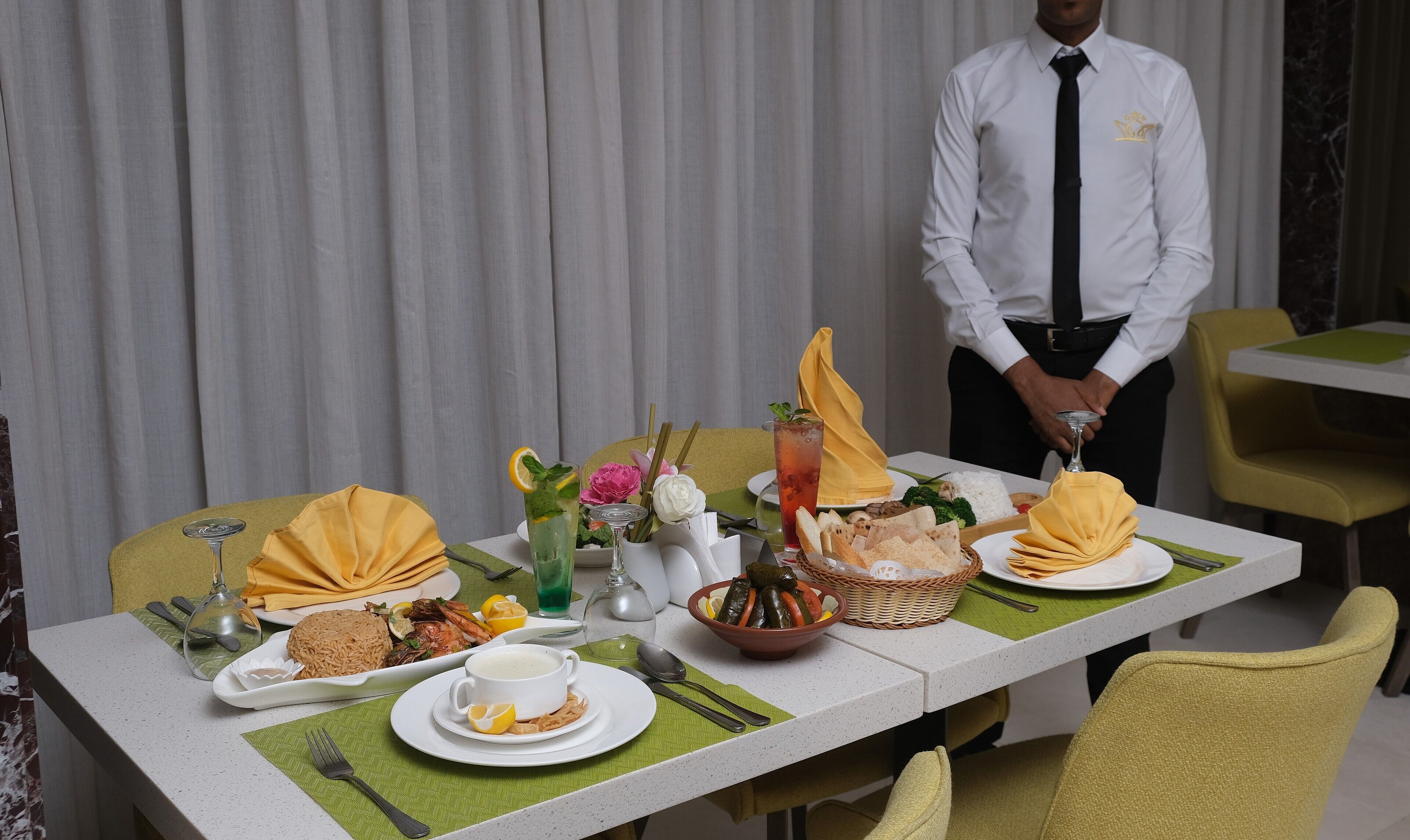 Une table à manger dressée dans un hôtel, avec différents plats, notamment du riz, des fruits de mer et des légumes.