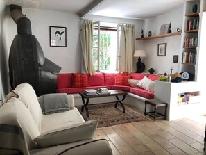Un salon avec un canapé rouge, un fauteuil blanc, une table basse et une cheminée.