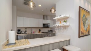A modern kitchen with a central island, bar stools, a microwave, and a hanging wine rack. - Charming Beachfront 3BR in Puntarena (Río Hato)