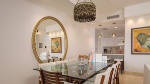 A dining area with a glass table surrounded by wooden chairs, a large mirror, and a chandelier. - Charming Beachfront 3BR in Puntarena (Río Hato)