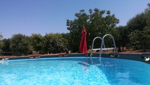 Una piscina azul cristalina con una escalera y una toalla roja sobre un soporte.