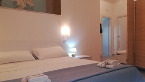 Una habitación de hotel con cama, mesita de noche, lámpara y puerta.