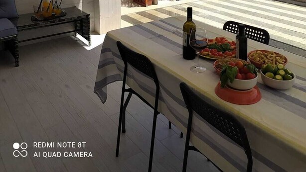 Un patio al aire libre con una mesa lista para comer, un sofá y una parrilla.