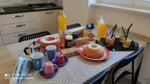 Un desayuno listo con una mesa, sillas y diferentes alimentos y bebidas.