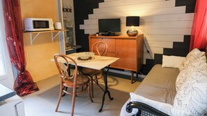 A compact room with a bed, a desk with a TV, a microwave, and a chair.