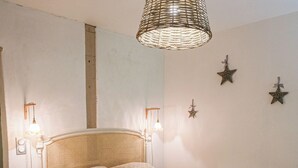 A bedroom with a bed, bedside lamps, a woven light fixture, and star-shaped wall decorations.