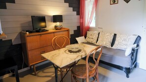 A compact living space with a dining table, a sofa, a TV, and a wooden cabinet.