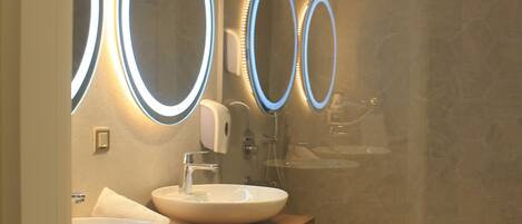A bathroom with two sinks, a mirror, and a shower.