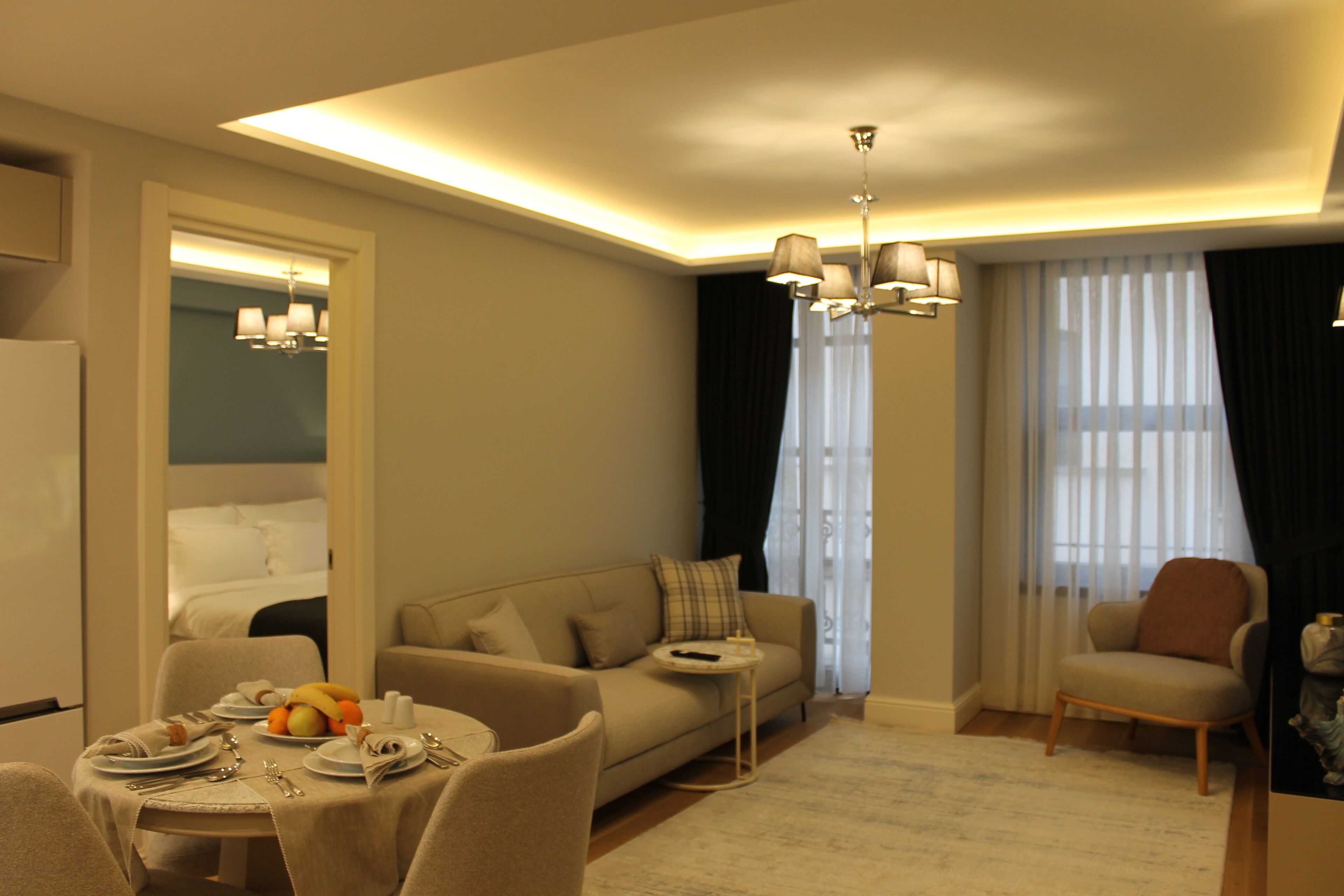 Une chambre d’hôtel comprenant un coin repas, un canapé, un fauteuil, une petite table ronde et un lit.
