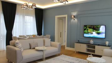 A modern living room with a sofa, coffee table, TV, and a dining area with a table and chairs.