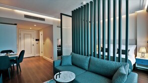 A modern hotel room with a sofa, a dining table, and a kitchen area visible through a partition. - Garlon Residence (Istanbul)