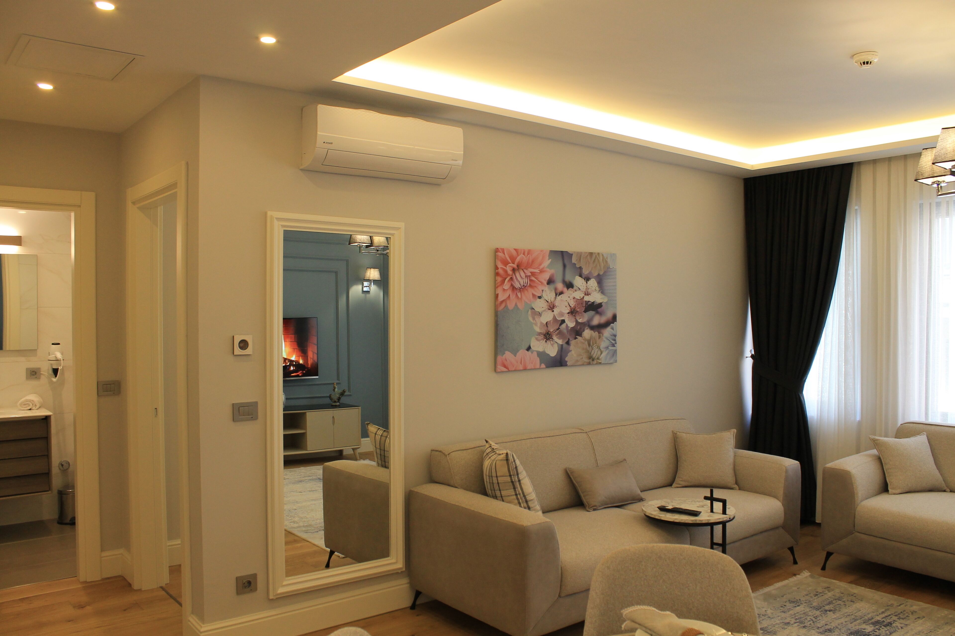A modern living room with a sofa, armchairs, a small coffee table, and a painting on the wall.