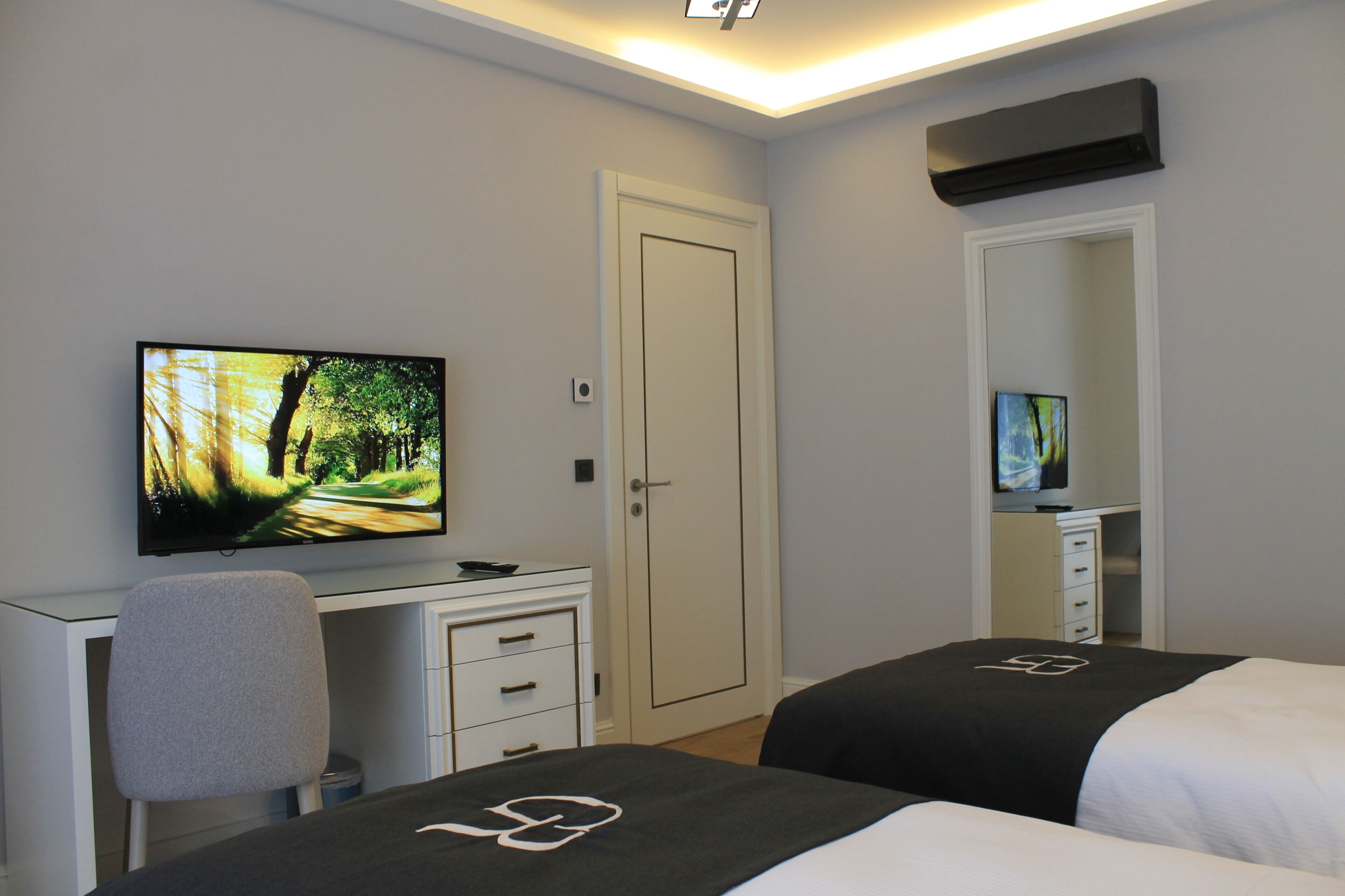 A hotel room with a bed, a desk, a chair, a television, and a wardrobe.