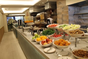A buffet with various fruits, vegetables, and prepared dishes.