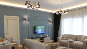 A living room with a sofa, a television, a dining table with plates and glasses, and a chandelier. - Garlon Residence (Istanbul)