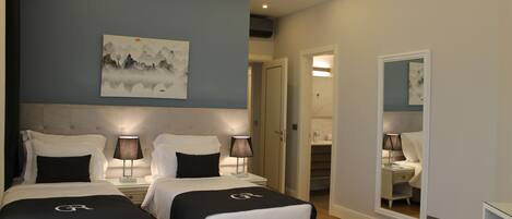 Une chambre d’hôtel avec deux lits, un tableau au mur, un miroir et un luminaire au plafond.