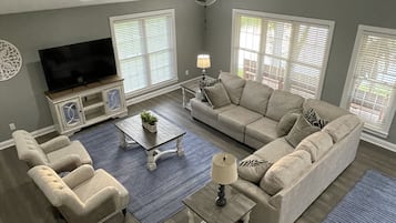 A living room with a sofa, armchairs, a coffee table, and a TV.