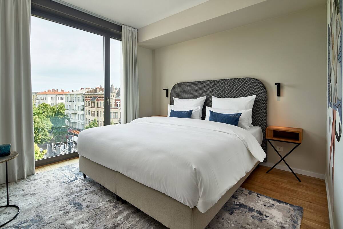 Une chambre d’hôtel moderne avec un grand lit, une vue sur la ville et une petite table d’appoint.