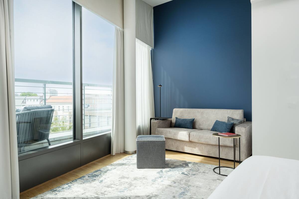 Une pièce moderne avec une grande fenêtre, un canapé, une petite table et un tapis.