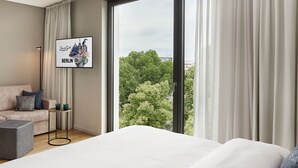Una habitación de hotel moderna con una cama grande, un sofá, una mesita y un cuadro enmarcado de Berlín.