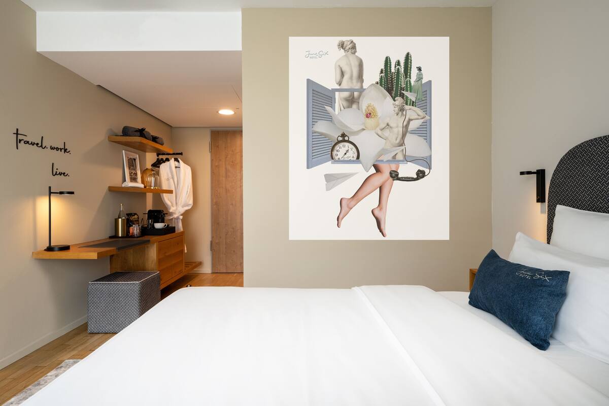 Une chambre à coucher moderne, comprenant un lit, une table de chevet, une commode et une œuvre d’art murale.