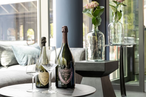 A table with a bottle of champagne and two glasses on a round table in a room with a view through a window. - June Six Berlin City West (Berlin)