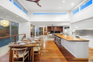 A modern kitchen with a central island, a dining area with a wooden table and chairs, and a large sliding glass door leading to a patio.