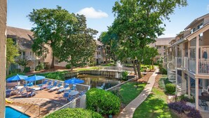 A courtyard with a swimming pool, lounge chairs, and a small bridge over a water feature. - Courtside 60 - 3BR Spacious Townhouse - Pool View - Short Walk to Beach (Hilton Head Island)