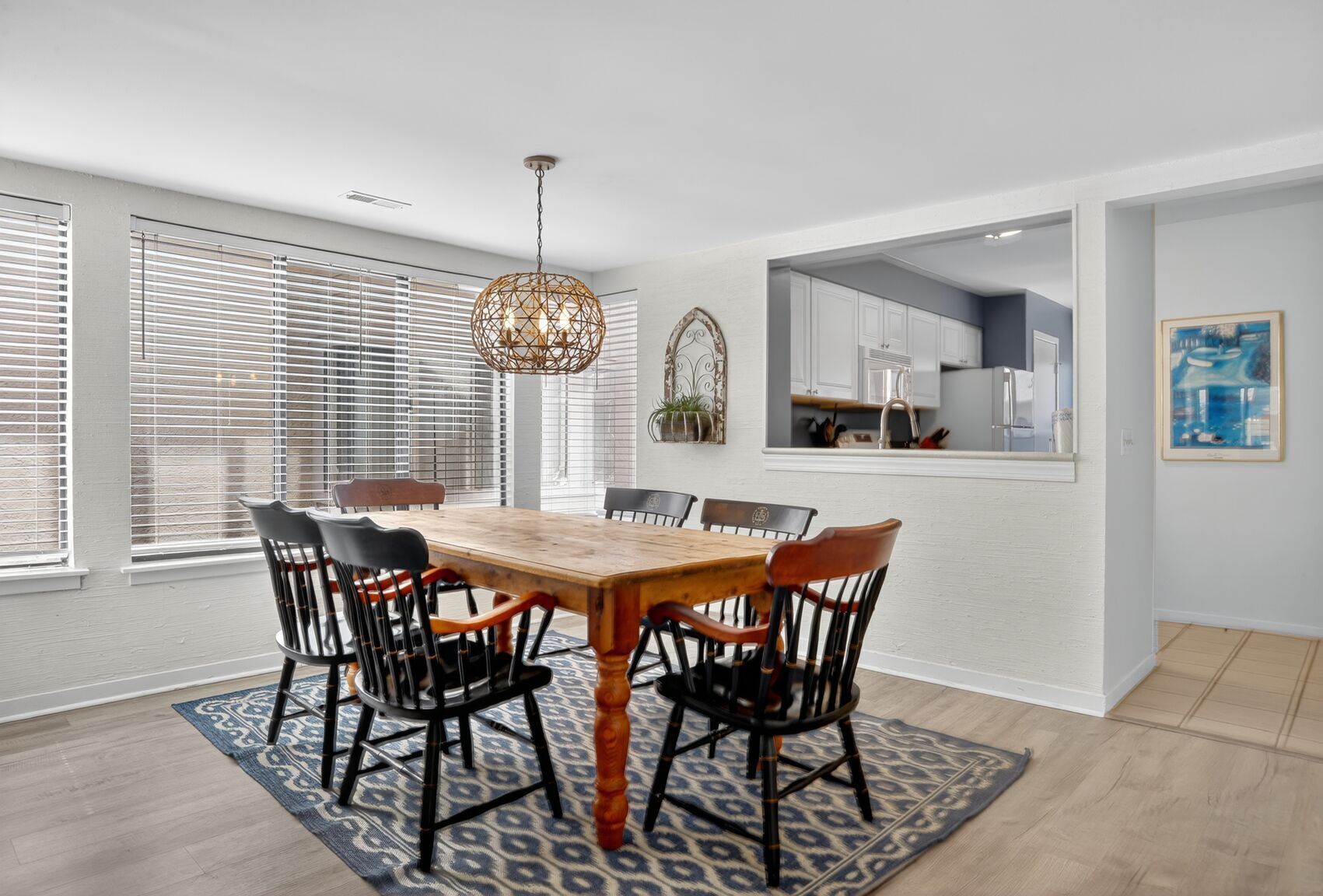 A dining area with a wooden table and chairs, a patterned rug, and a hanging light fixture.