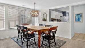 A dining area with a wooden table and chairs, a patterned rug, and a hanging light fixture. - Courtside 60 - 3BR Spacious Townhouse - Pool View - Short Walk to Beach (Hilton Head Island)