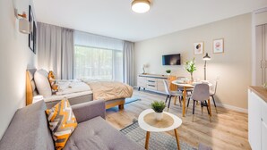 A modern, well-lit bedroom with a bed, sofa, and a dining area with a table and chairs. - Apartamenty Sun & Snow Solny Resort (Kolobrzeg)
