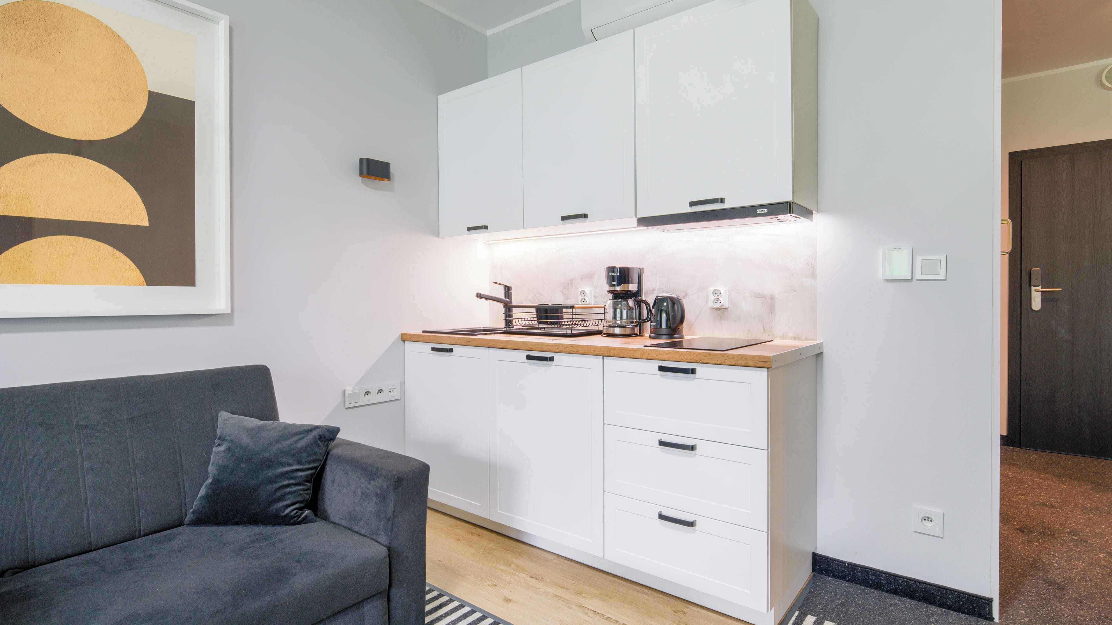 Una cocina compacta con armarios blancos, cafetera y tostadora.