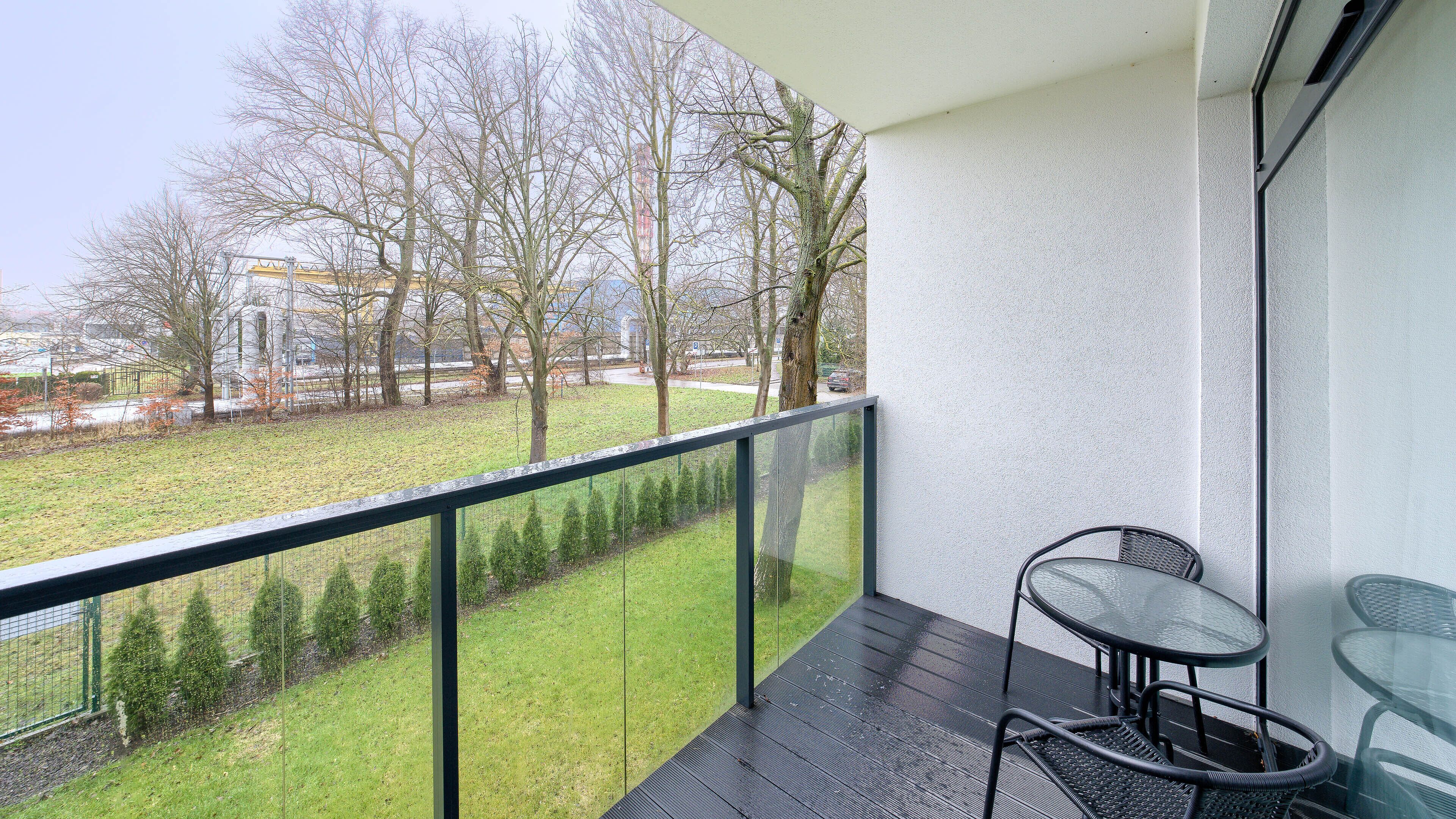Ein Balkon mit Glasgeländer, einem kleinen Tisch und einem Stuhl.