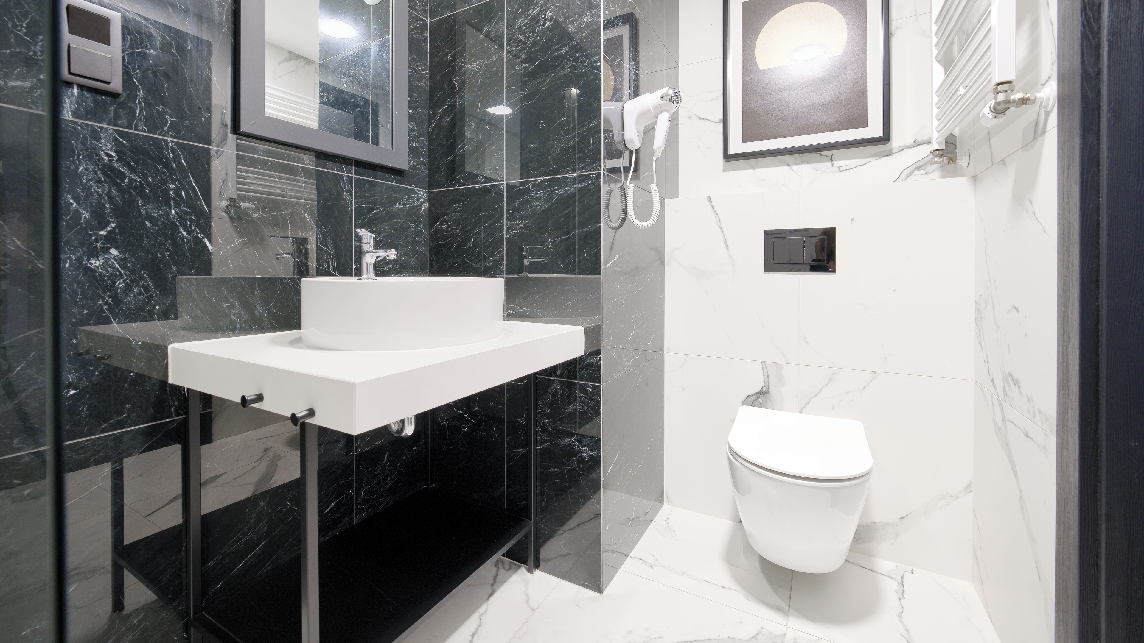 A modern bathroom with a white sink, a mirror, a toilet, and a hairdryer.