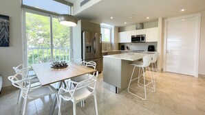 A modern kitchen with white cabinetry, stainless steel appliances, and a central island with bar stools. - Deluxe 2BR Marina Dockside Dreams (Río Hato)